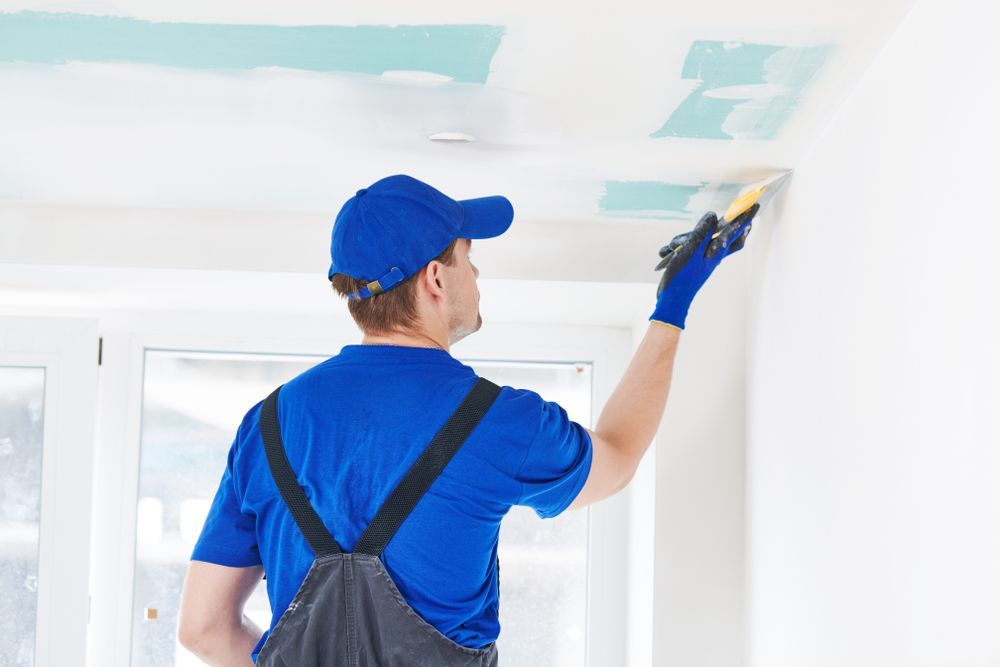 A Person is Plastering a Ceiling — Handyman Bundaberg In Burnett Heads, QLD