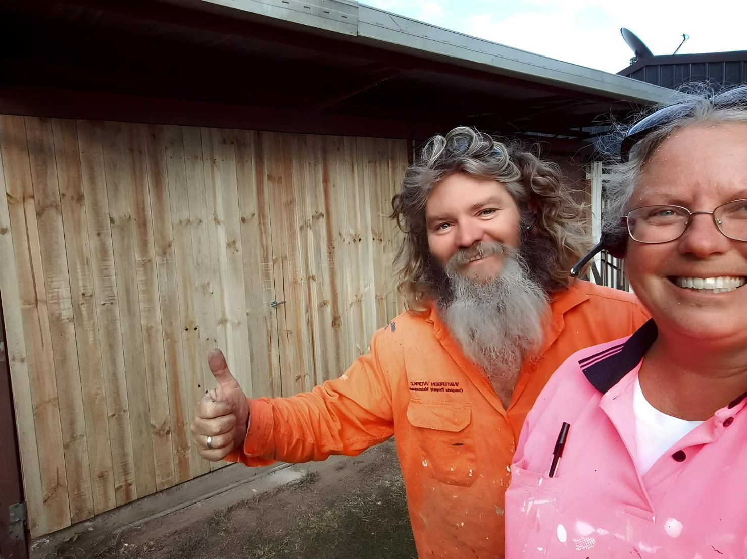 A Man With a Beard is Giving a Thumbs Up Next to a Woman in a Pink Shirt — Handyman Bundaberg In Burnett Heads, QLD