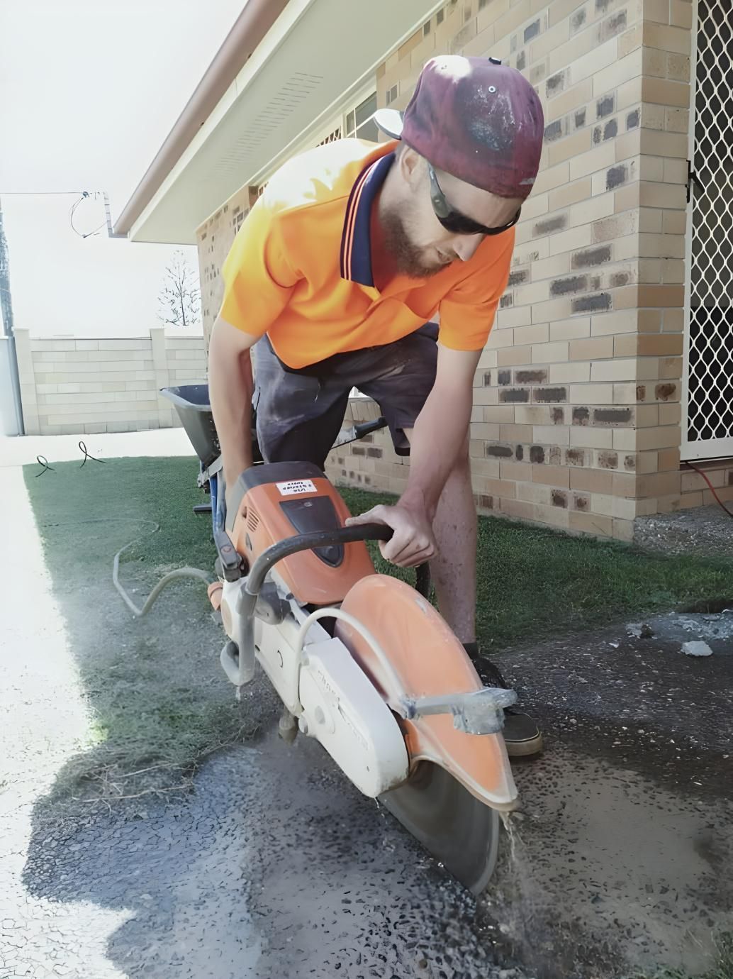 A Man in an orange Shirt is Working With Power Tools— Handyman Bundaberg In Burnett Heads, QLD