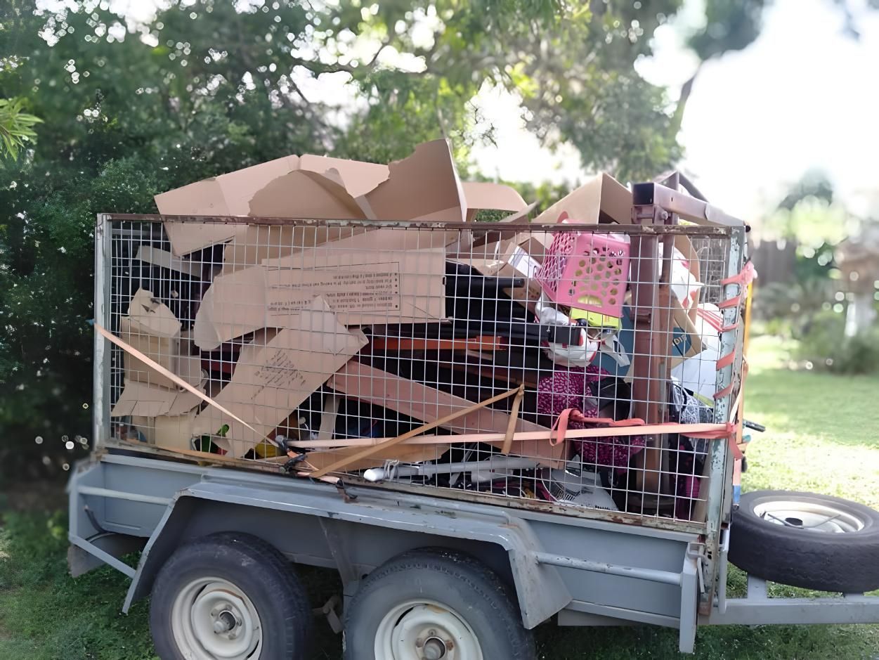 A Trailer Filled With Cardboard Boxes is Parked in the Grass — Handyman Bundaberg In Burnett Heads, QLD