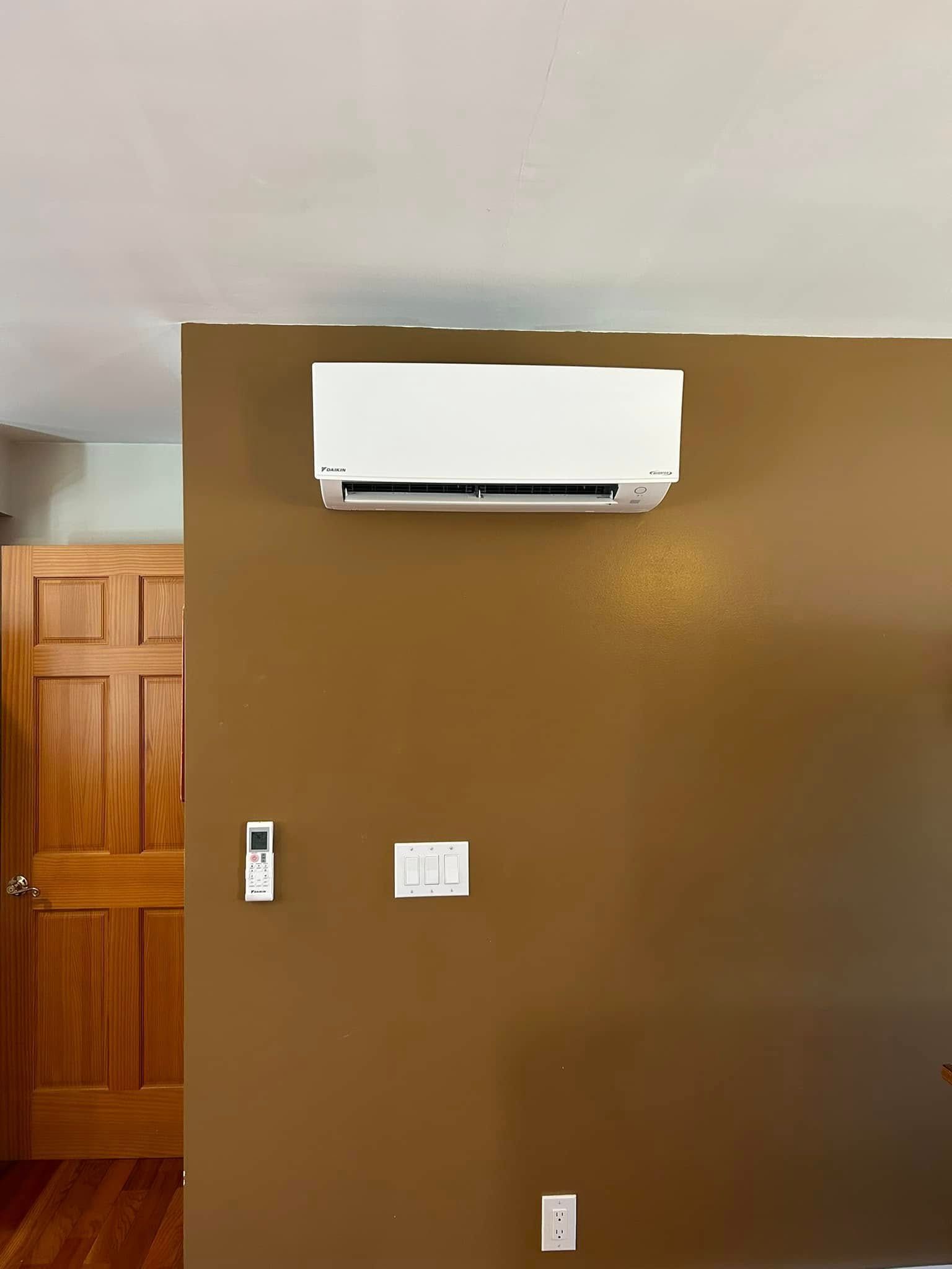A room with brown walls and a white air conditioner mounted on the wall.