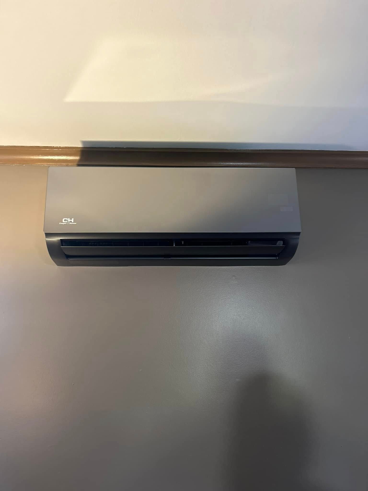 A black air conditioner is hanging on a wall in a room.