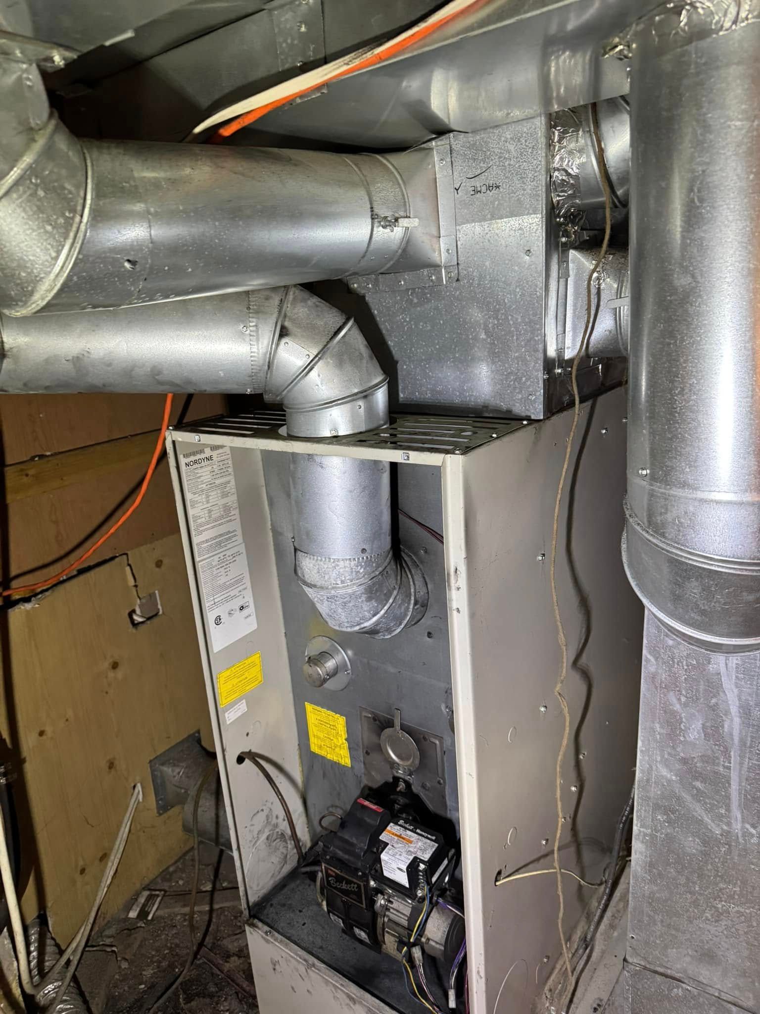A heater is sitting in a room with a lot of pipes coming out of it.