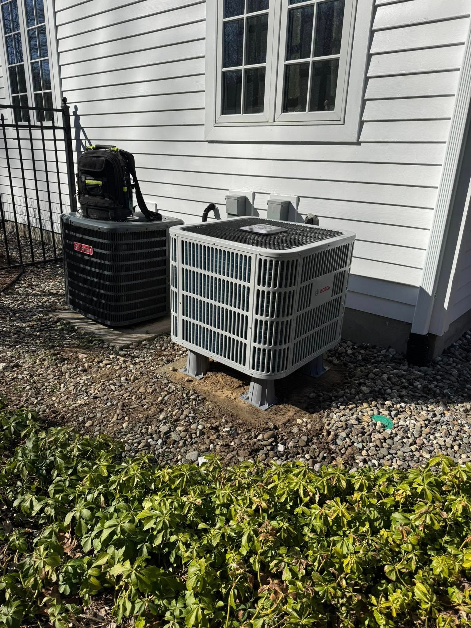 A couple of air conditioners are sitting on the side of a house.