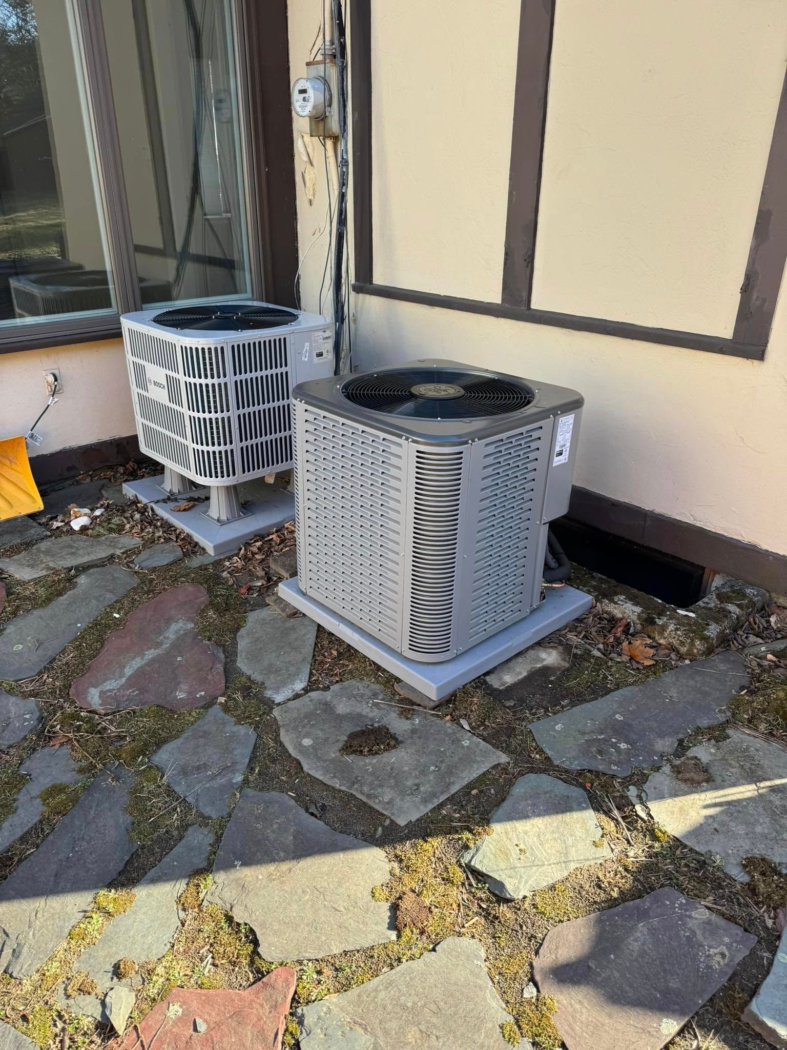Two air conditioners are sitting on the side of a building.