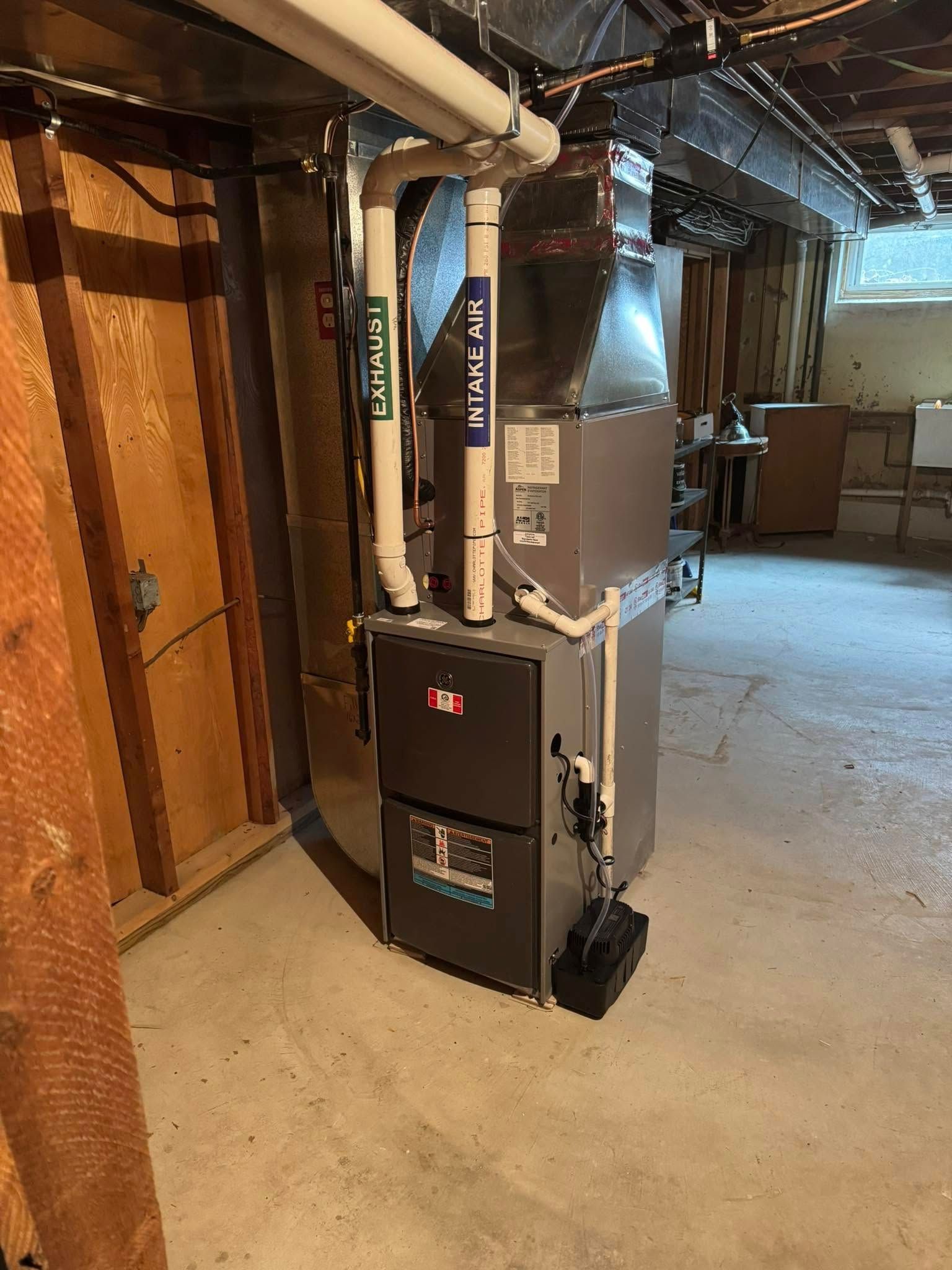 A furnace is sitting in a basement next to a wooden wall.