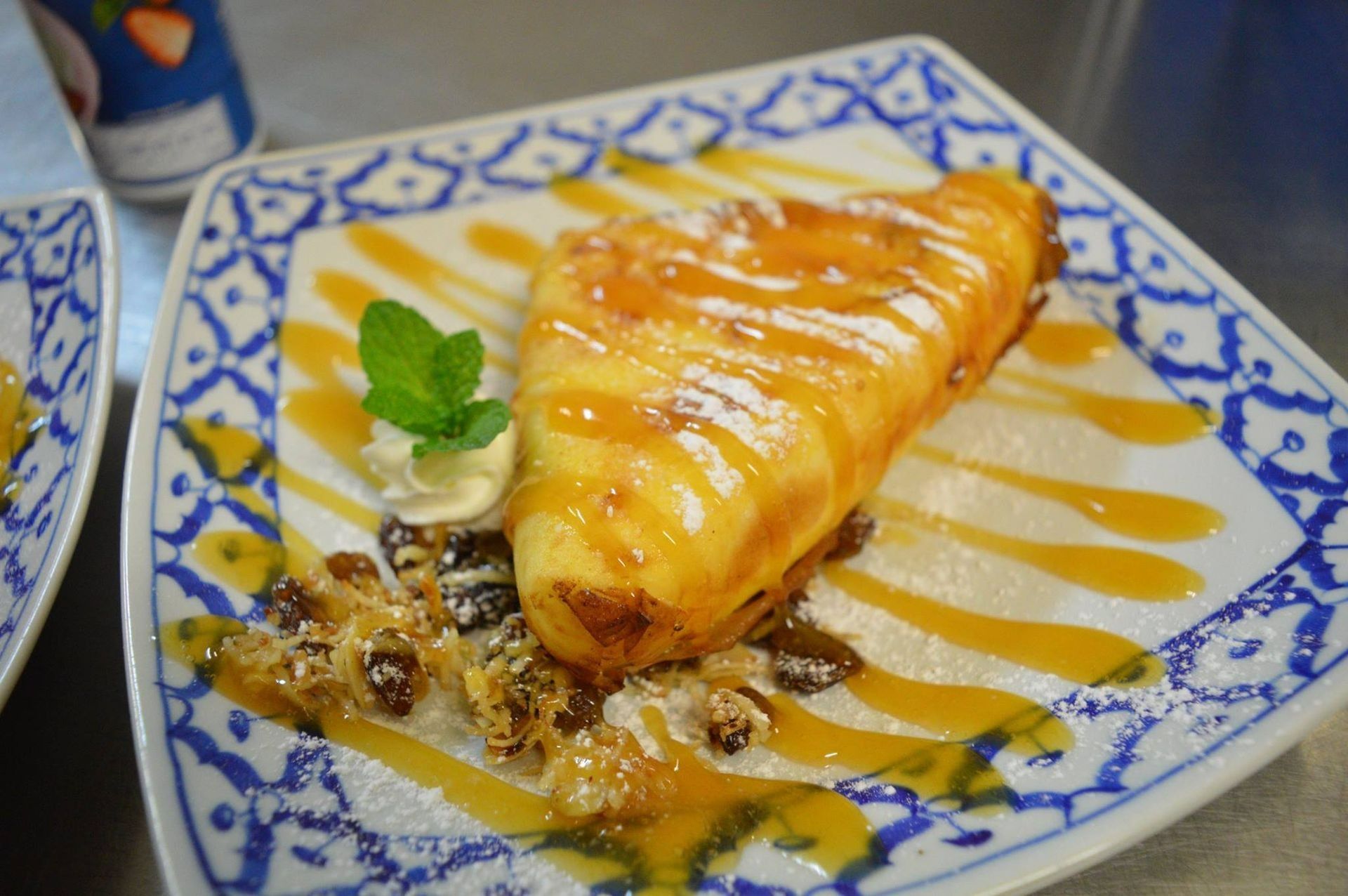Crepe With Caramel Drizzle, Raisins, and Whipped Cream on a Patterned Plate — Thai Taste Restaurant in Norman Gardens, QLD