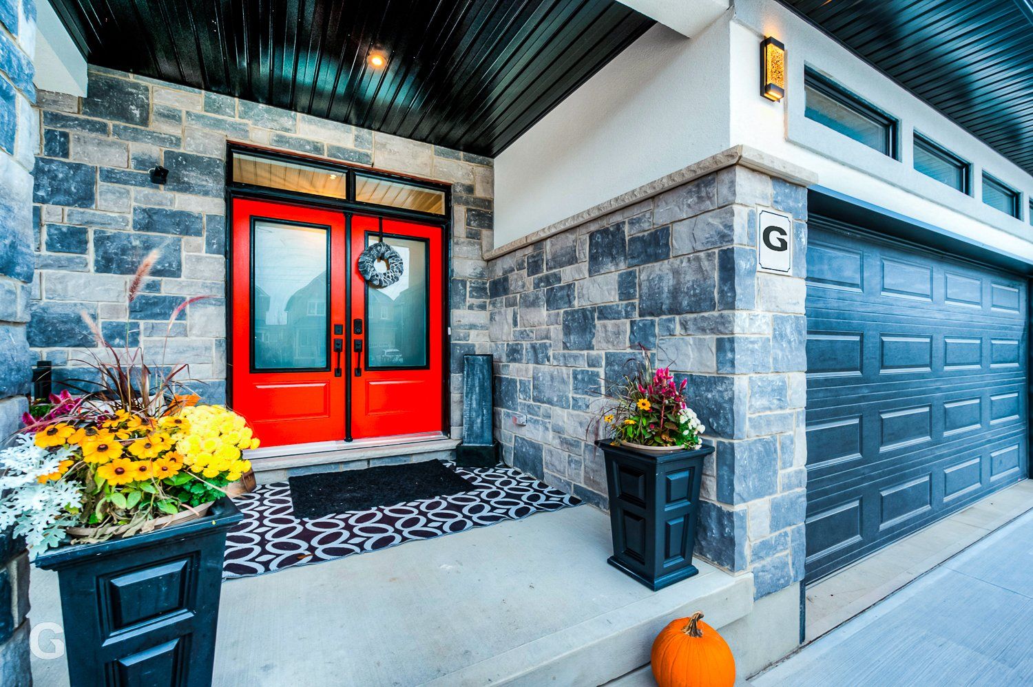 The front of a house with a red door and a black garage door.