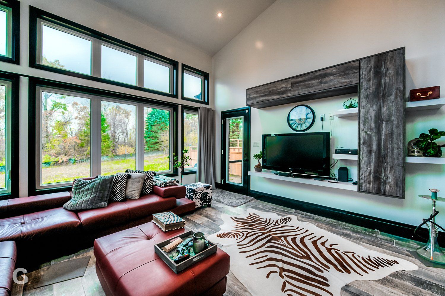 A living room with a couch , ottoman , rug and television.
