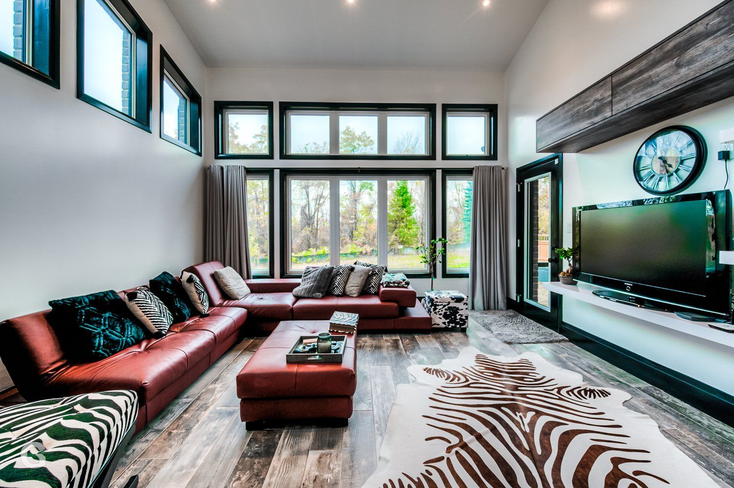 A living room with a large sectional couch , ottoman , and television.