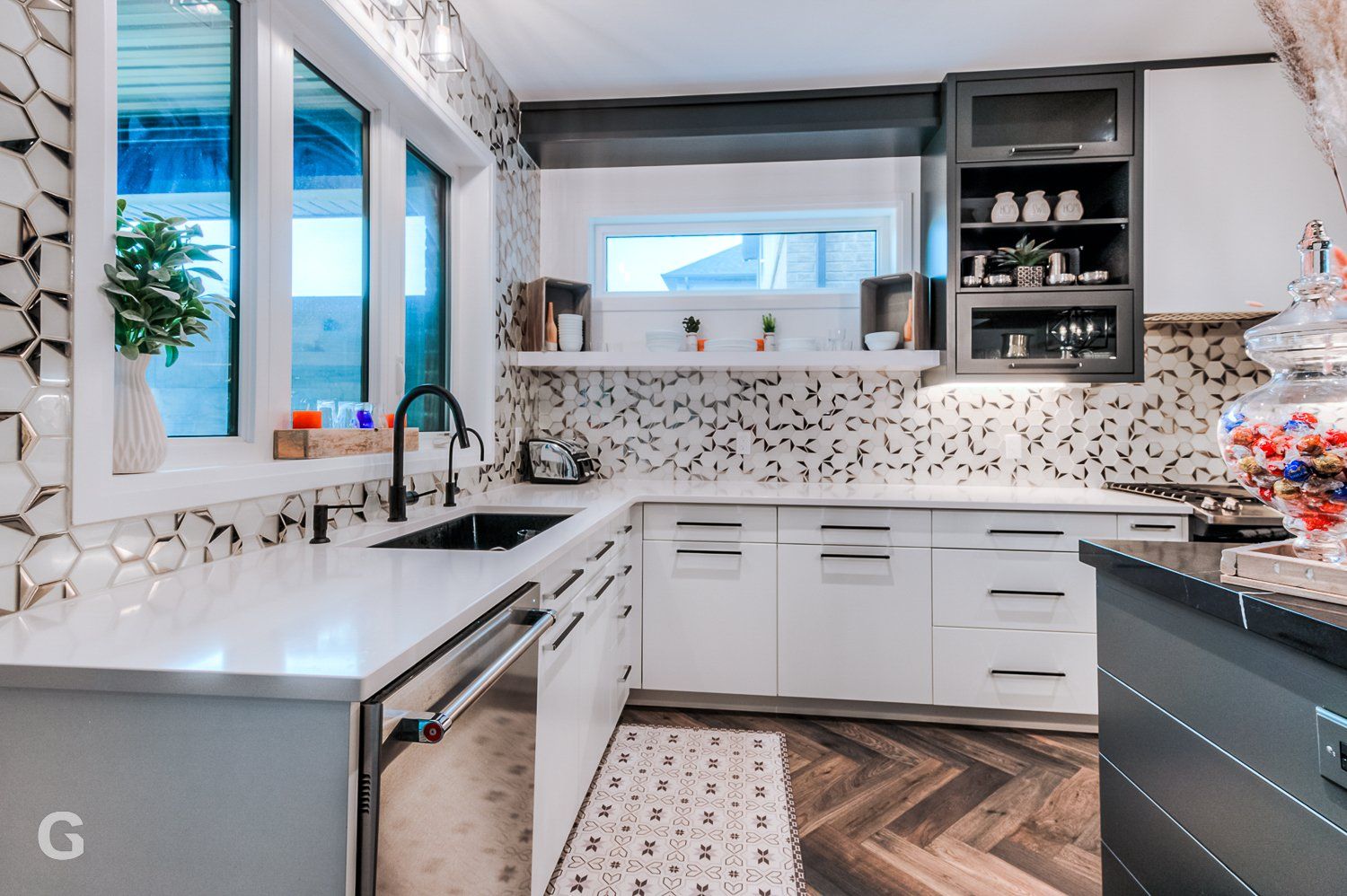 A kitchen with white cabinets , stainless steel appliances , a sink , and a herringbone floor.