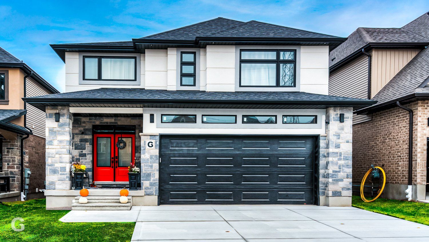 A large house with a red door and a black garage door.