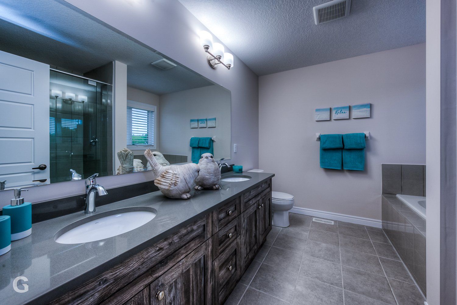 A bathroom with two sinks , a toilet , and a large mirror.