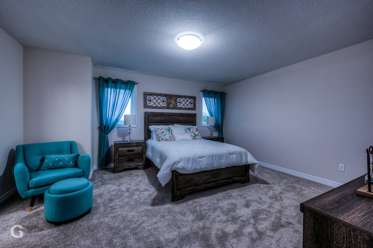 A bedroom with a bed , chair , ottoman and nightstand.