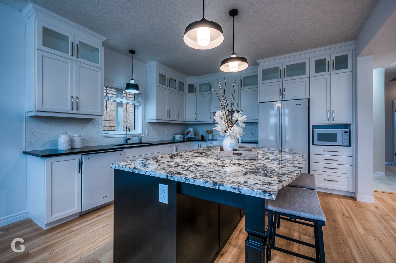 A kitchen with white cabinets , granite counter tops , stainless steel appliances and a large island.
