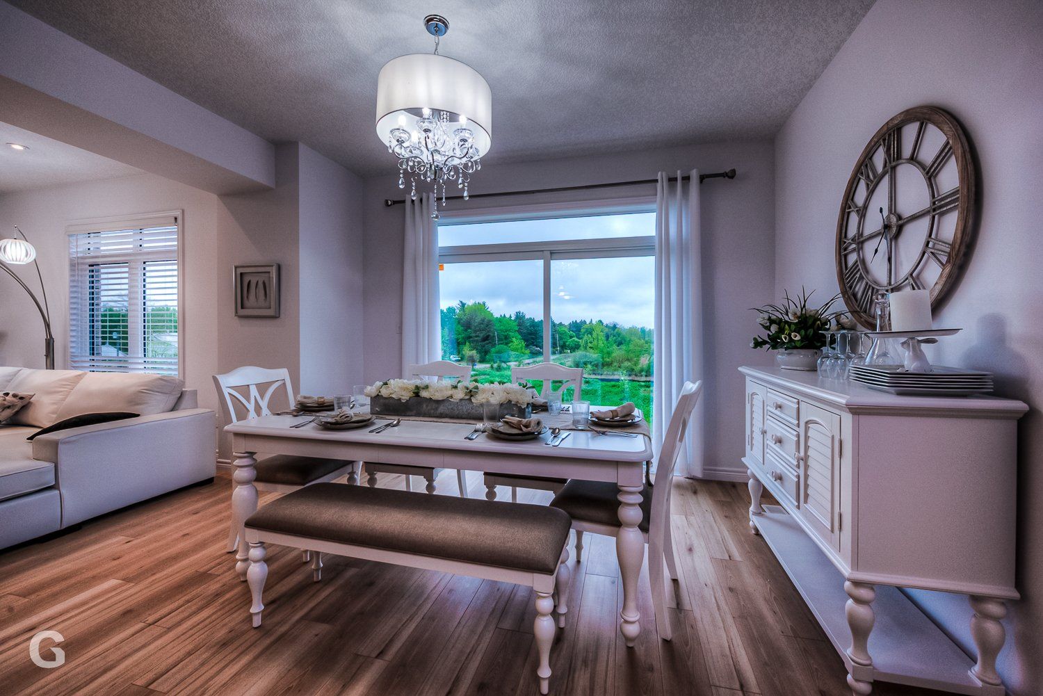 A dining room with a table and chairs and a clock on the wall