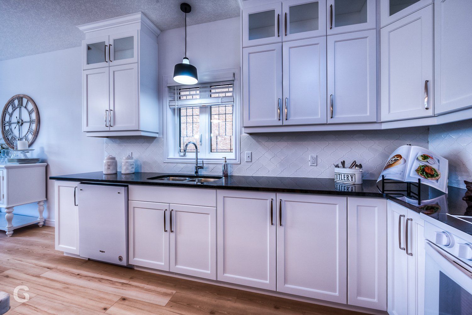 A kitchen with white cabinets , black counter tops , and a sink.