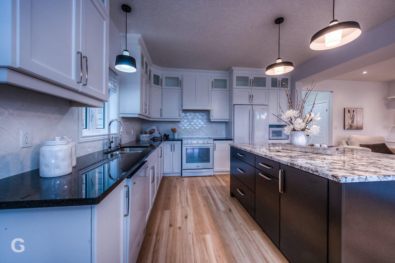 A kitchen with white cabinets and black counter tops