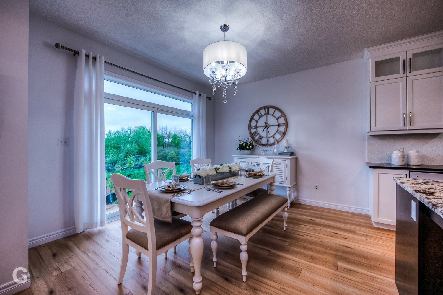 A dining room with a table and chairs and a clock on the wall.