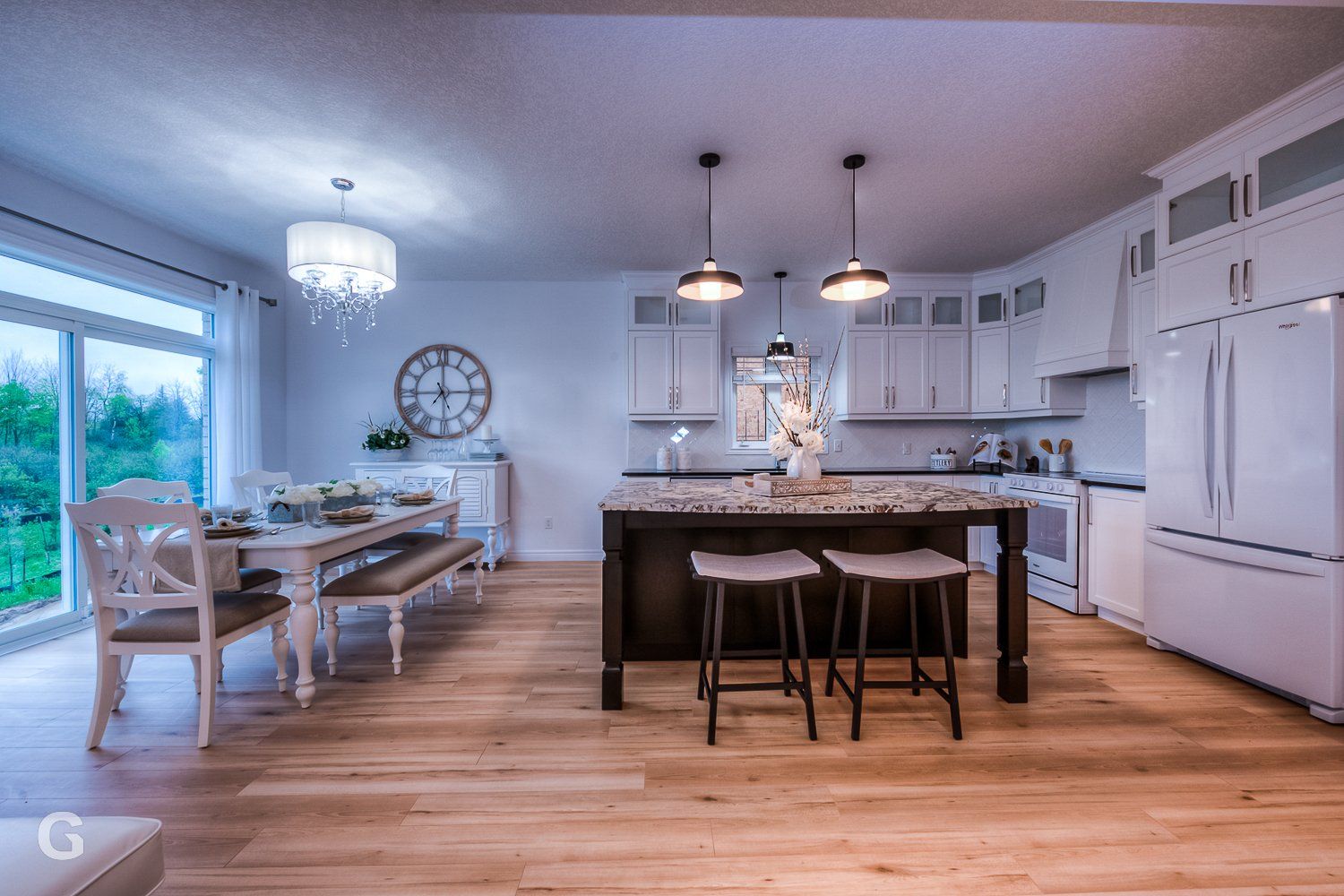 A kitchen with a large island , stools , a table and chairs.