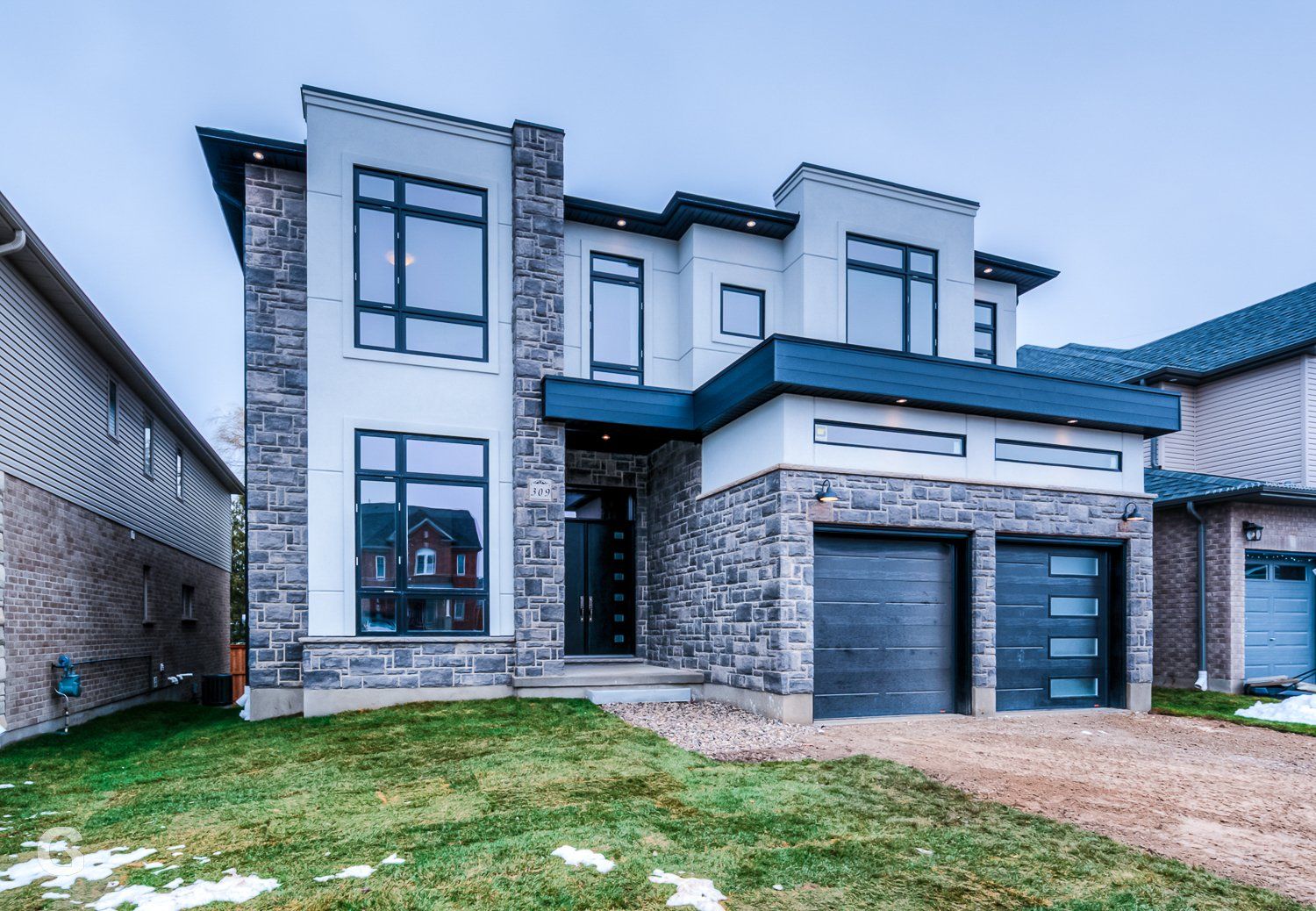 A large house with two garages is sitting on top of a lush green lawn.