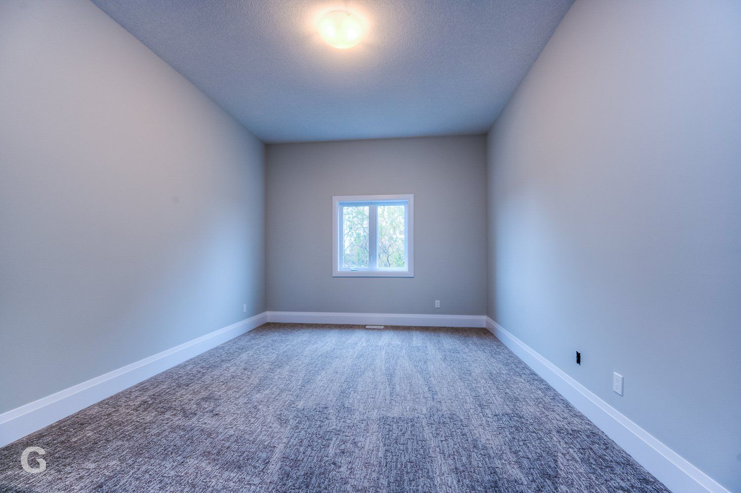 An empty room with a window and a carpeted floor
