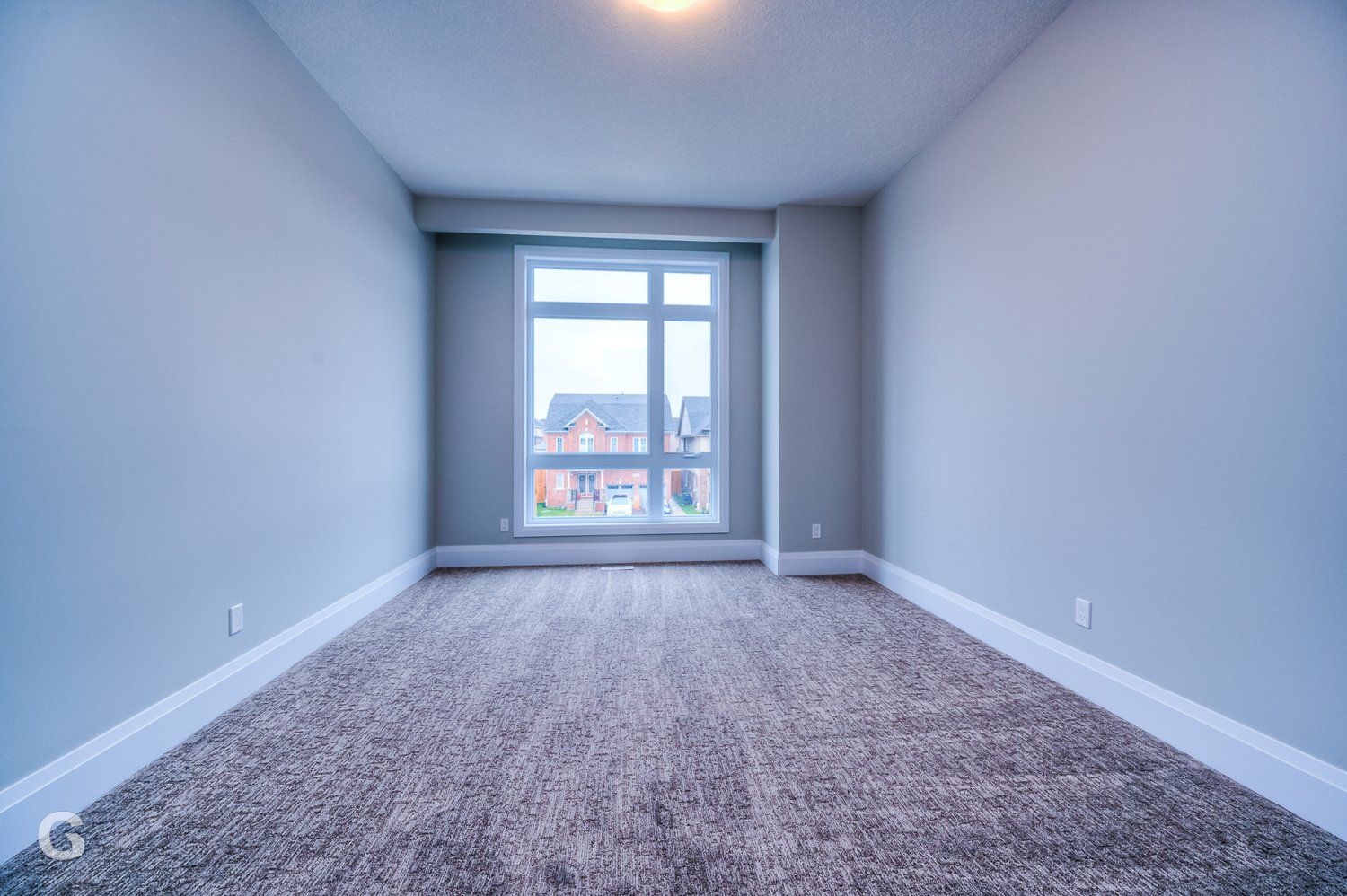 An empty bedroom with a large window and a carpeted floor.