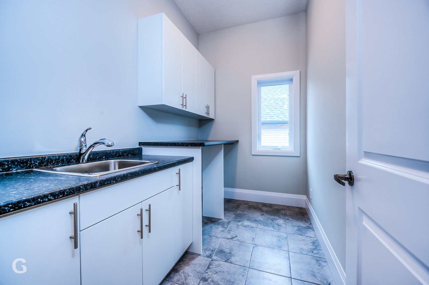 A kitchen with white cabinets and a sink and a window
