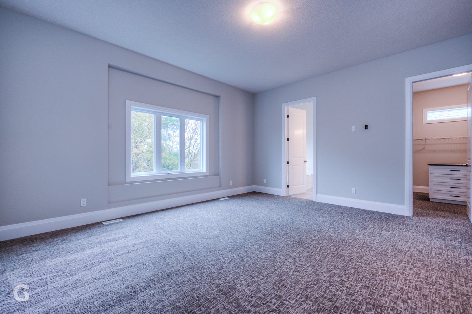 An empty bedroom with a carpeted floor and a window.