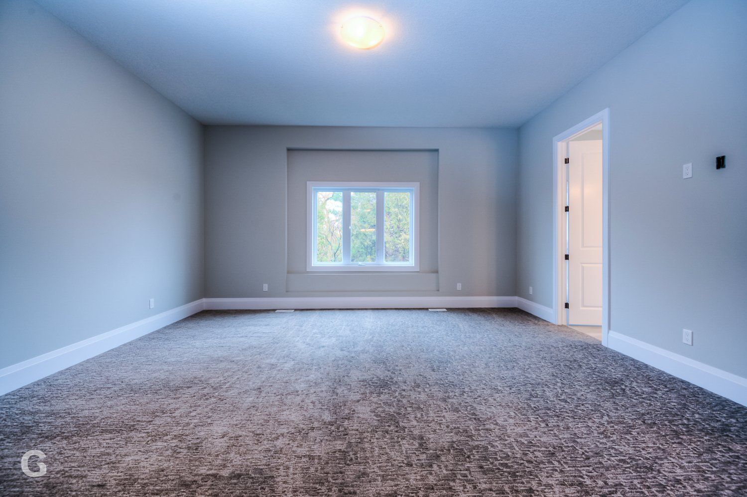 An empty room with a carpeted floor and a window.