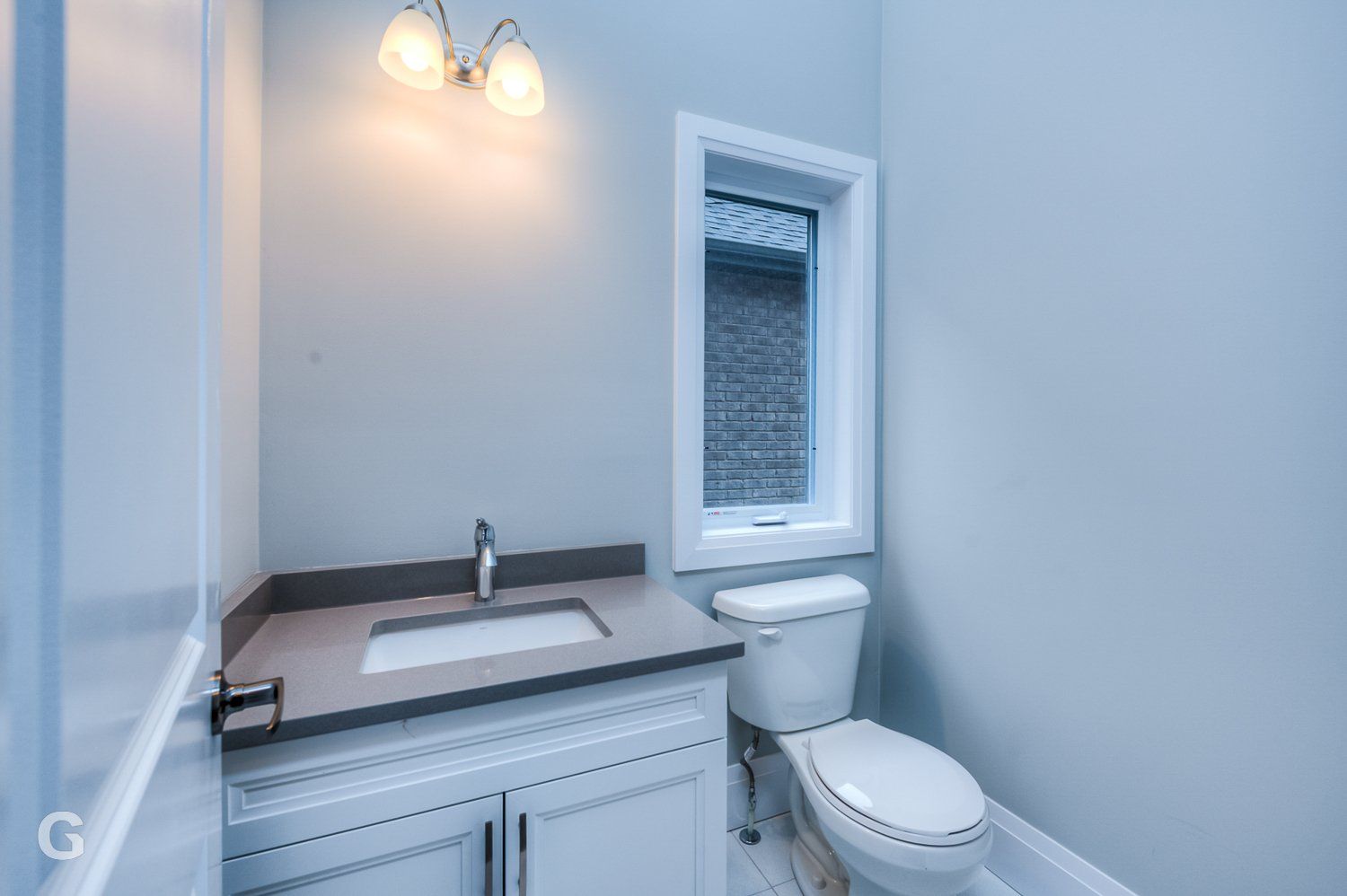 A bathroom with a sink , toilet and window.