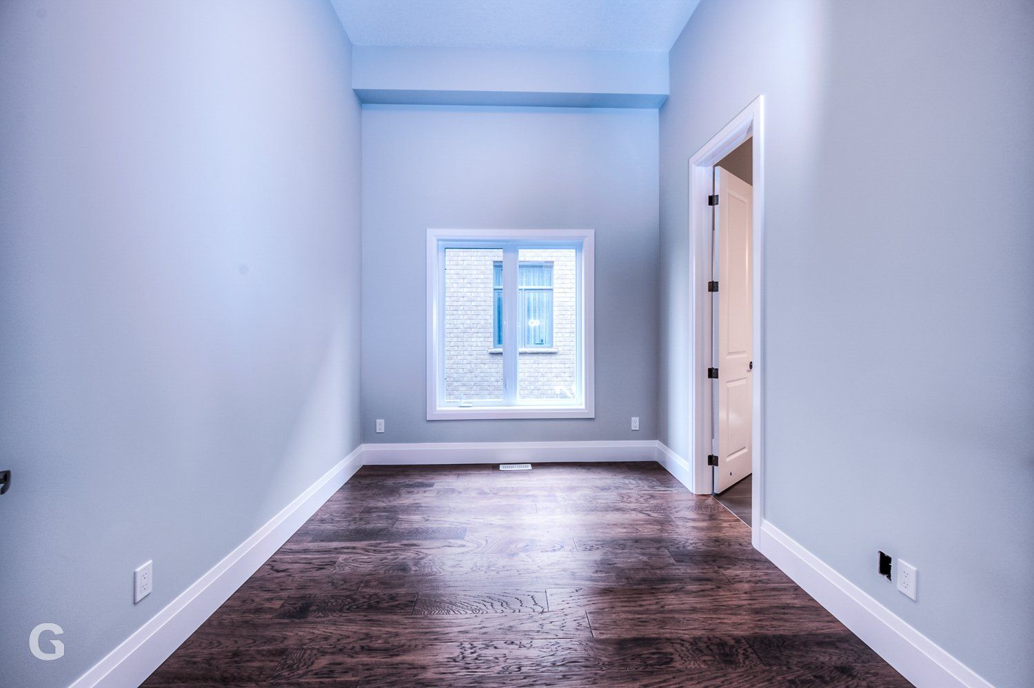 An empty room with hardwood floors and a window.
