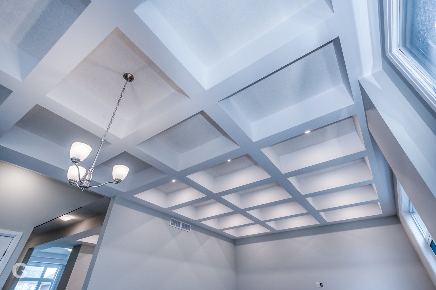 A room with a coffered ceiling and a chandelier hanging from it.