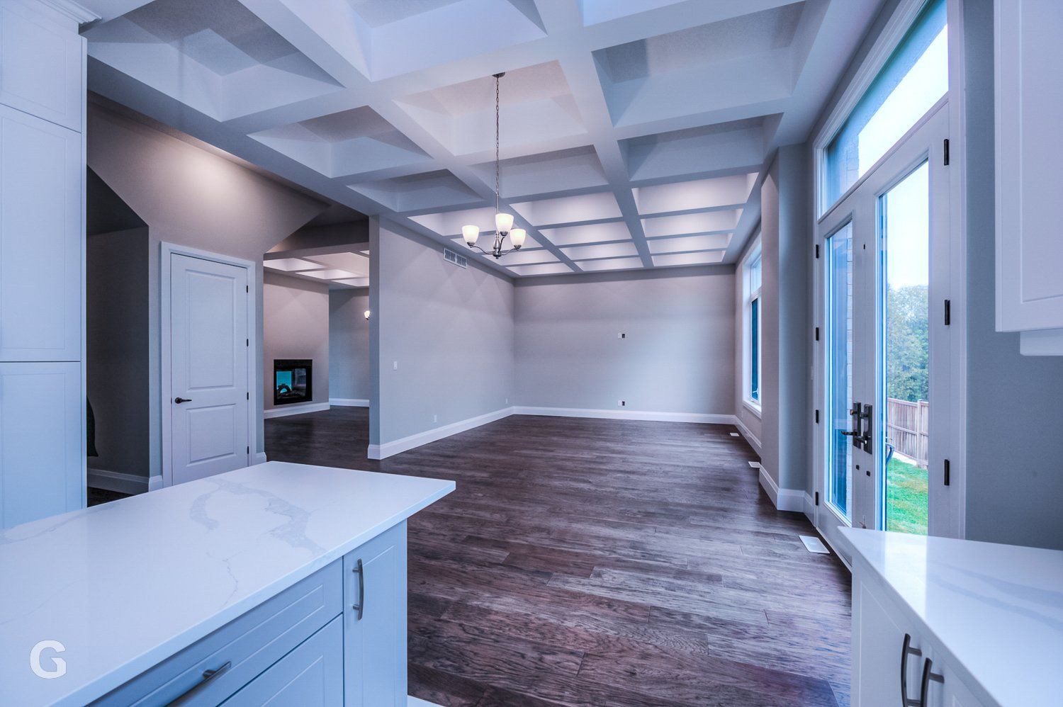 A large empty room with hardwood floors and a coffered ceiling.