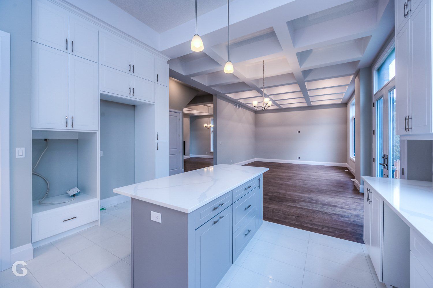 An empty kitchen with white cabinets and a large island.