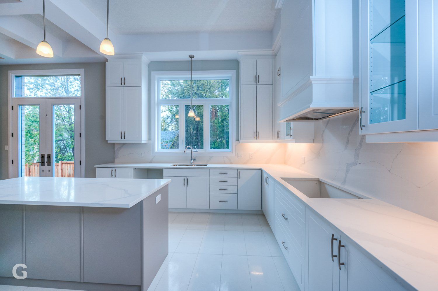 An empty kitchen with white cabinets and a large island.