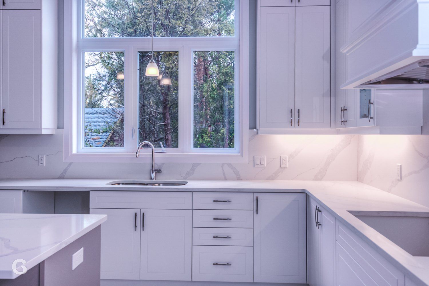 A kitchen with white cabinets and a large window