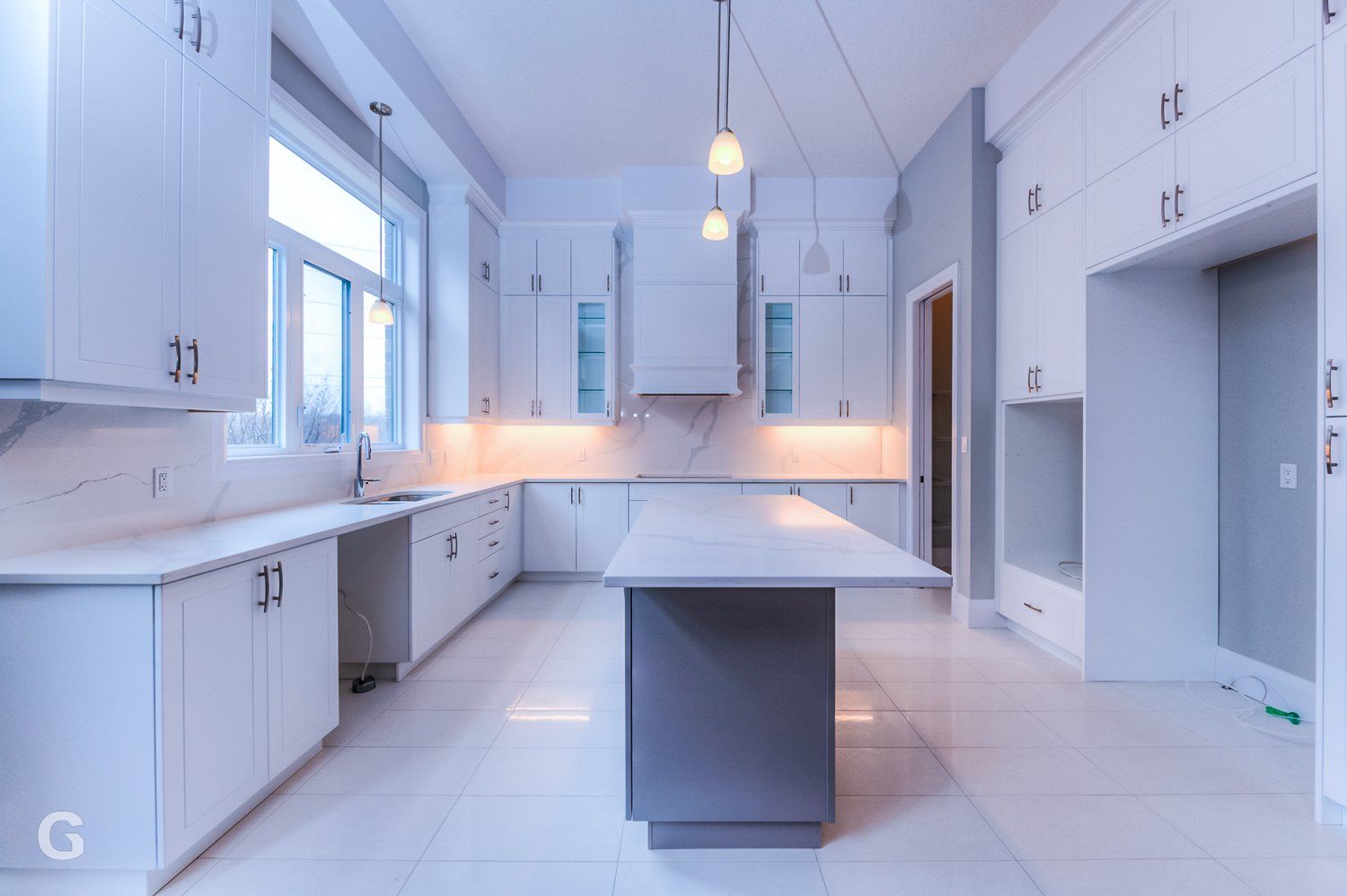 An empty kitchen with white cabinets and a large island.