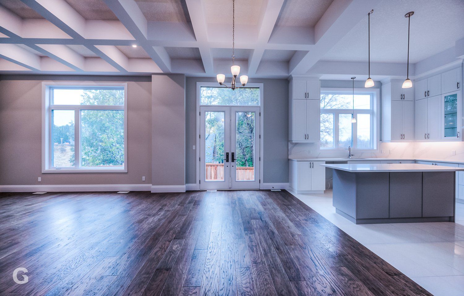 A large empty room with hardwood floors and a kitchen