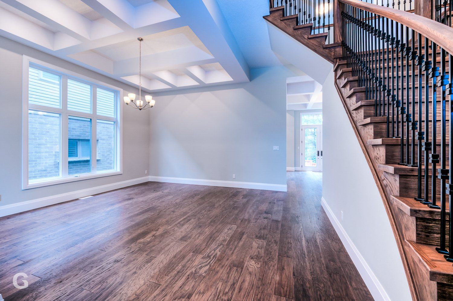 An empty living room with hardwood floors and stairs in a house.