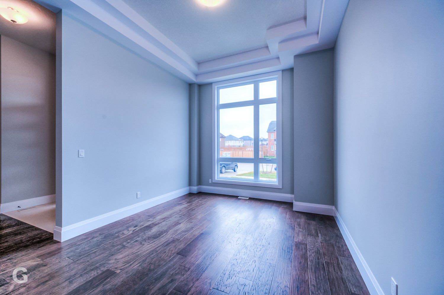 An empty room with hardwood floors and a large window.