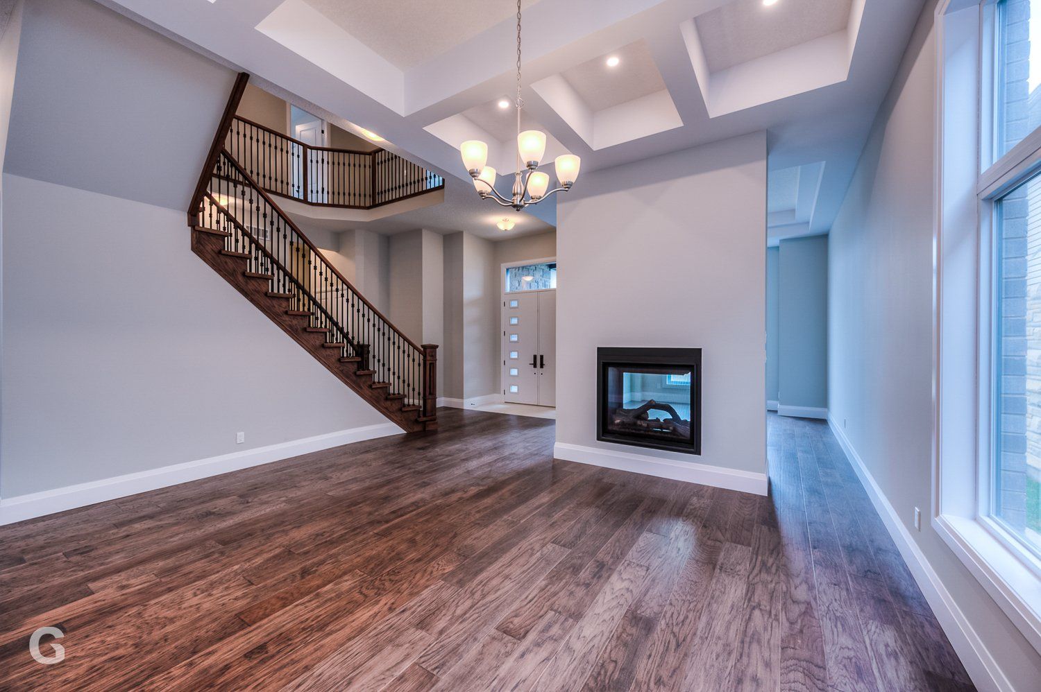 An empty living room with hardwood floors and a fireplace.