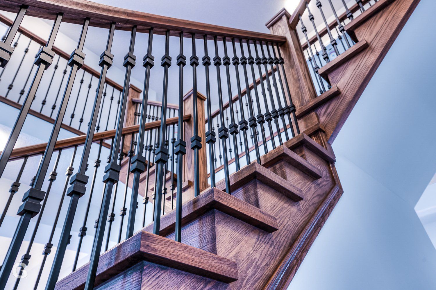 A close up of a wooden staircase with a wrought iron railing.