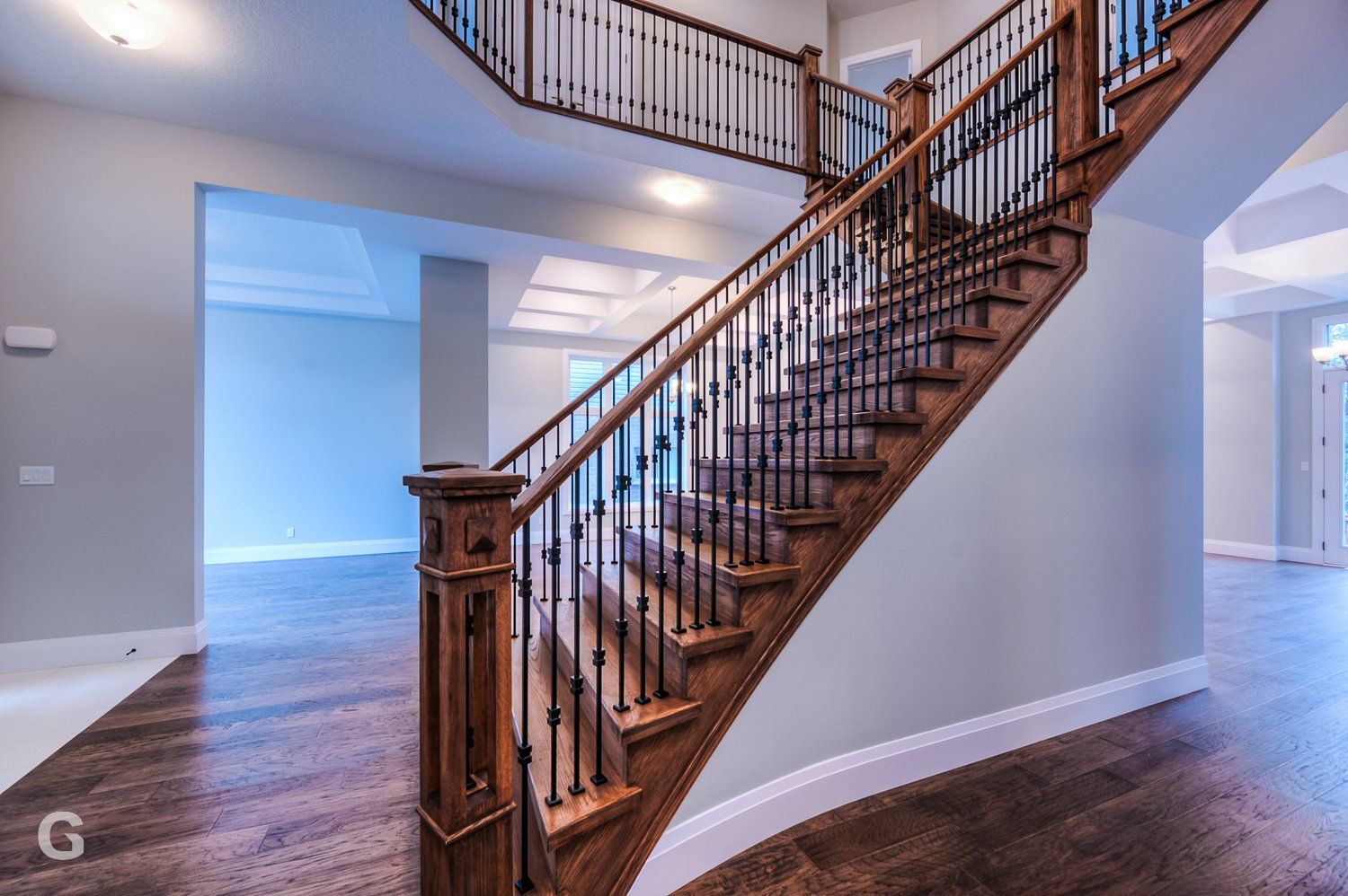 A wooden staircase with a metal railing in an empty house.