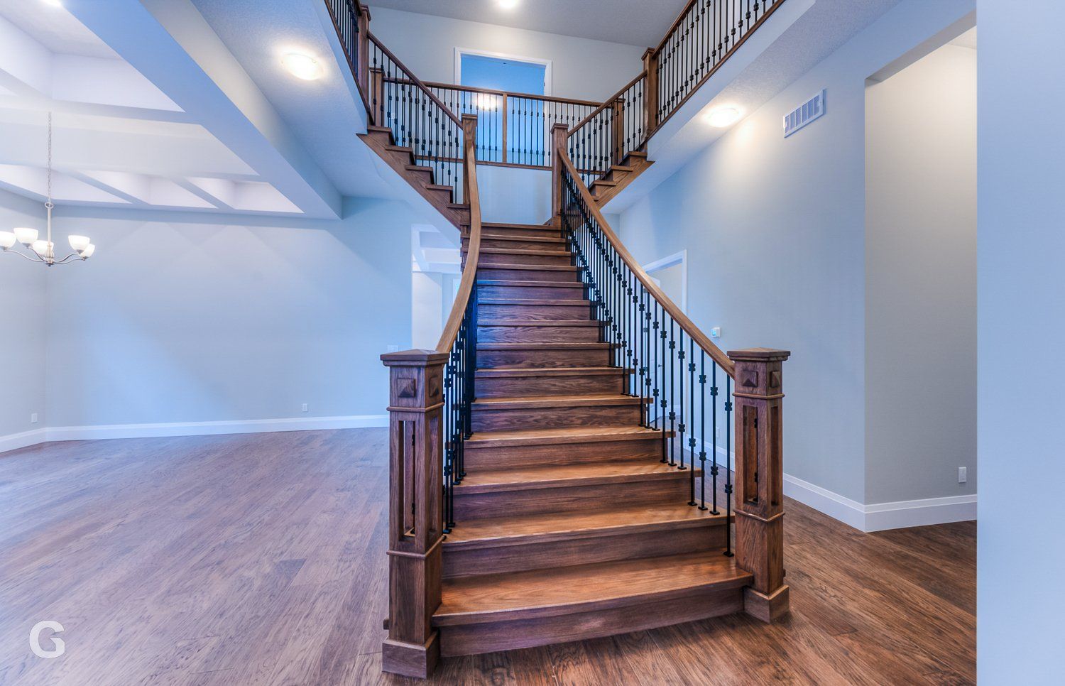 A wooden staircase with a wrought iron railing in an empty room