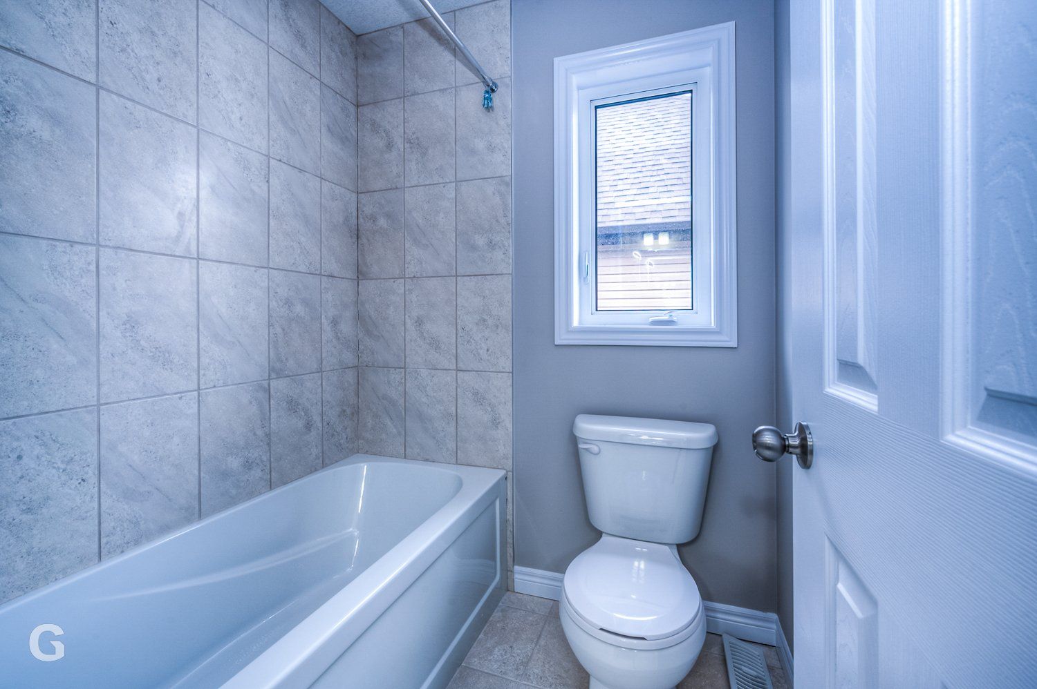 A bathroom with a toilet , bathtub and window.