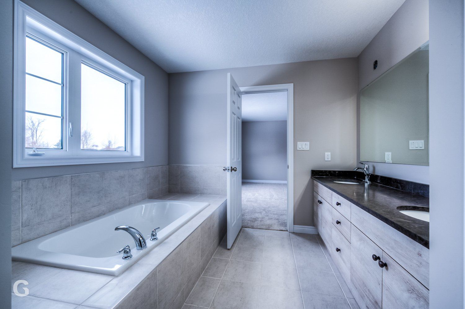 A bathroom with a tub , sink , mirror and window.
