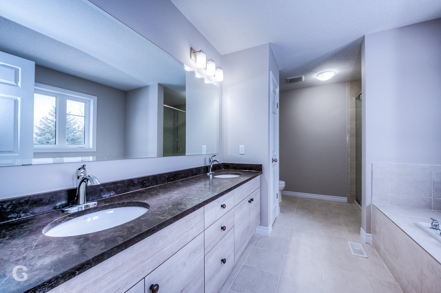 A bathroom with two sinks and a large mirror.