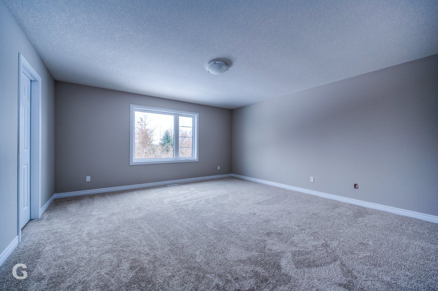 An empty room with a carpeted floor and a window.