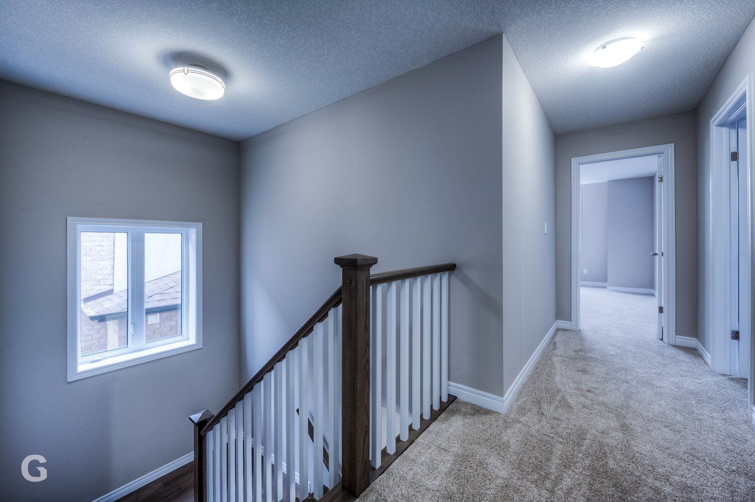 A hallway with a staircase and a window in a house.